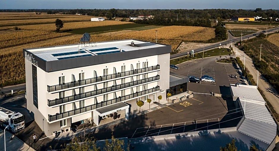 a large white building with a green roof and several cars parked in front of it at Hotel River