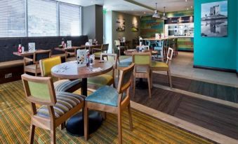 a restaurant with various dining tables and chairs , some of which are occupied by people at Premier Inn Oban