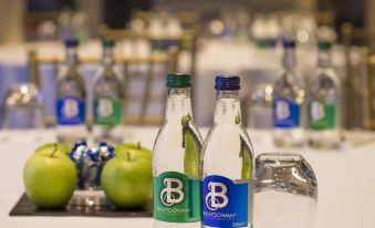 a table with two bottles of water and a green apple on it , as well as other bottles of water in the background at Kilkea Castle