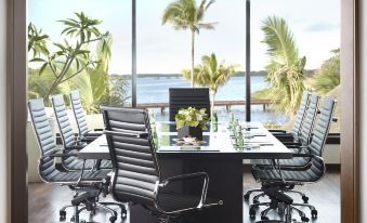 a dining room with a table set for a meal , surrounded by chairs and a view of the ocean at Four Seasons Resort Mauritius at Anahita