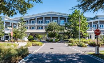 a large building with a covered entrance is surrounded by trees and bushes , with a parking lot in front at WaterSound Inn