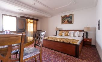 a hotel room with a large bed , a dining table , and a painting on the wall at Royal Elmount Hotel