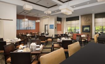 a large , well - lit restaurant with multiple dining tables and chairs arranged for guests to enjoy their meal at DoubleTree by Hilton Dulles Airport - Sterling