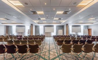 a large conference room with multiple rows of chairs arranged in a semicircle , facing a projector screen at Crowne Plaza Reading