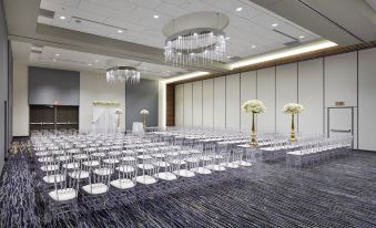 a large , empty banquet hall with rows of white chairs and chandeliers hanging from the ceiling at InterContinental Hotels Minneapolis - ST. Paul Airport