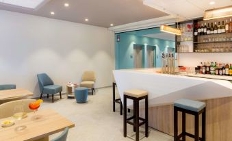 a modern and clean waiting room with blue chairs , a white counter , and a wooden bar at Best Western Hotel le Semaphore