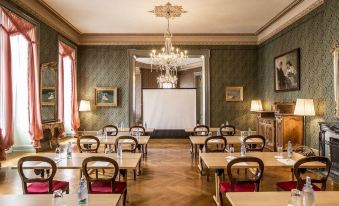 a conference room with wooden floors and chairs arranged in rows , along with a projector screen on the wall at Grandhotel Giessbach