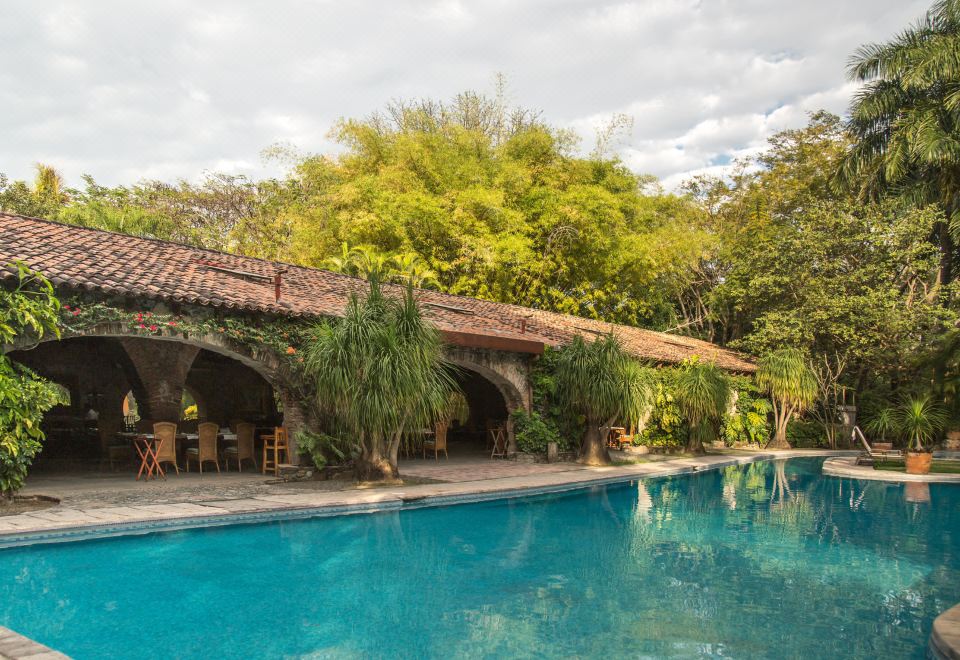 a large swimming pool surrounded by lush greenery , with several chairs placed around the pool area at Hacienda San Gabriel de las Palmas