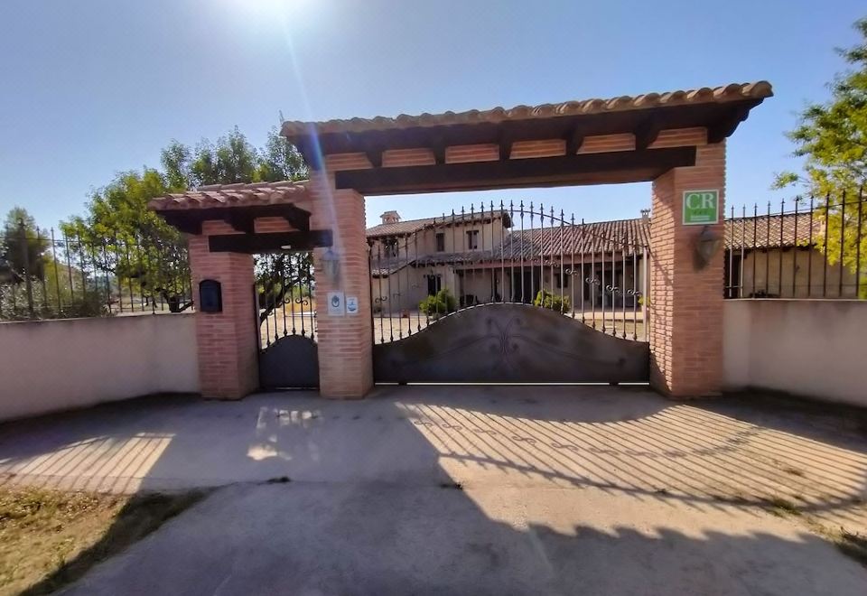 a brick building with a gate and a car parked in front of it , under the sun at La Contrada