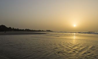 a serene beach scene at sunset , with the sun setting over the ocean and its reflection on the calm water at Sunset Beach Hotel