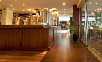 a large room with wooden floors and a long counter , featuring several beer tanks on the right side at Markets Hotel