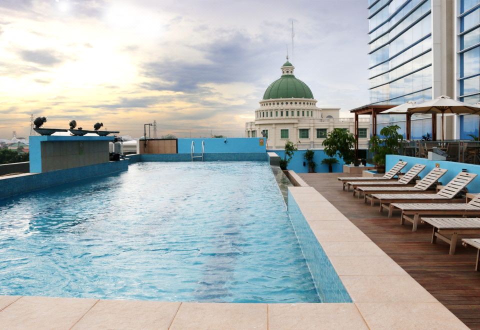 a large swimming pool with a building in the background and lounge chairs around it at Java Palace Hotel