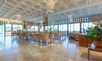 a large dining room with multiple tables and chairs arranged for a group of people to enjoy a meal together at Golden Sand Hotel