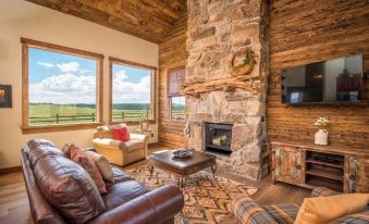 a cozy living room with a brown leather couch , a television , and a fireplace at Zion Mountain Ranch