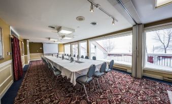 a large conference room with a long table and chairs , a projector screen , and windows at Hotel Verso