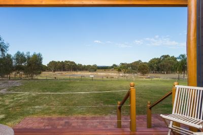 a beautiful view of a golf course from a wooden deck , with clear blue skies and green trees in the background at The Swan Valley Retreat