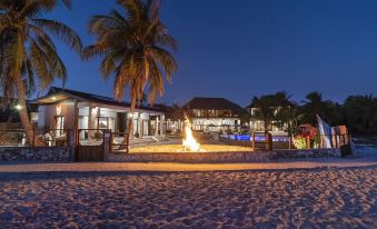 a beach scene with a building in the background and a fire pit in the foreground at Manduna Resort