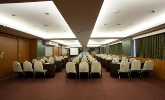 a large conference room with rows of chairs and tables , a projector screen at the front at Bay Hotel Srinakarin