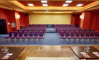 a large conference room with rows of purple chairs arranged in an auditorium - style seating arrangement at Central Plaza Hotel