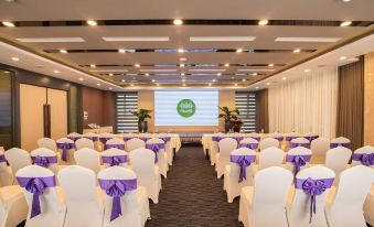 a conference room set up for a meeting , with chairs arranged in rows and a projector on the wall at Purple Lotus Hotel