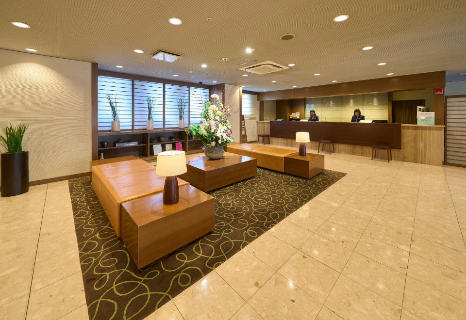 a hotel lobby with a reception desk , wooden benches , and a potted plant , creating a welcoming atmosphere at Hotel Resol Machida