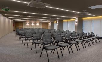 a large conference room with rows of black chairs arranged in a semicircle , providing seating for a large group of people at Slaviero Campina Grande