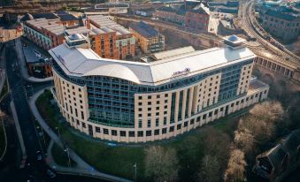 aerial view of a modern building with multiple floors and large windows , surrounded by trees and buildings at Hilton Newcastle Gateshead