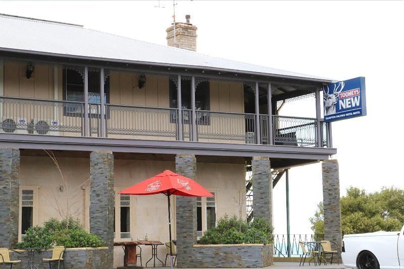 a house with a red umbrella and outdoor seating area on the porch , under a cloudy sky at Hampton Halfway Hotel Motel