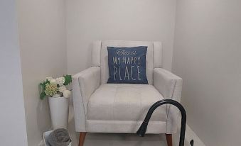 "a white chair with a blue pillow that says "" love at the end "" is placed in a corner next to a sink" at Pelican Beach Hotel