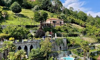 a large villa on a hillside with a pool and lush greenery surrounding it , providing a picturesque view at Hotel Bazzoni