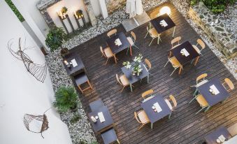 an aerial view of a wooden patio with tables and chairs , surrounded by plants and rocks at Art Hotel