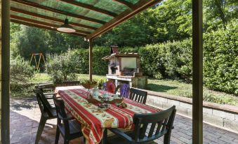 a covered outdoor dining area with a table , chairs , and a fireplace , surrounded by trees and grass at Girasole