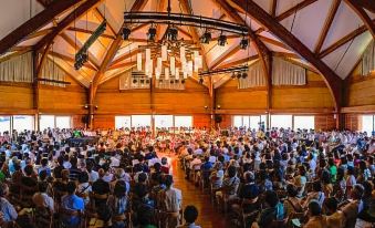 a large group of people are gathered in a room with wooden walls and ceiling at Okushiga Kogen Hotel