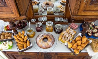 a table is set with a variety of desserts and pastries , including a cake , donuts , and croissants at Syros Atlantis