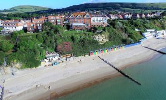 a bird 's eye view of a beach with colorful umbrellas and houses in the background at Grand Hotel Swanage