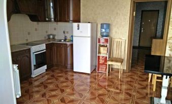 a kitchen with brown cabinets , a refrigerator , and a tv mounted on the wall , as well as a dining table and chairs at Luxury Apartment