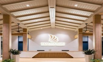 A spacious room with a lit ceiling and walls covered in wood panels, located next to the lobby at Panwaburi Beachfront Resort