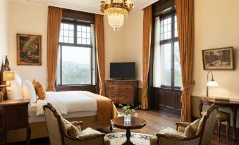 a spacious bedroom with a large bed , a couch , and a tv . also a dining table in the room at Schloss Lieser, Autograph Collection