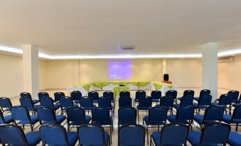 a conference room with blue chairs arranged in rows and a projector screen on the wall at Gran Hotel de Lago - El Coca