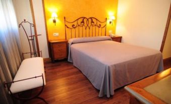 a hotel room with a large bed , a wooden dresser , and two lamps on the wall at Rivera del Duero