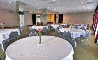 a large , empty banquet hall with white tablecloths and chairs , decorated with flowers and vases of flowers at Silver Beach Hotel