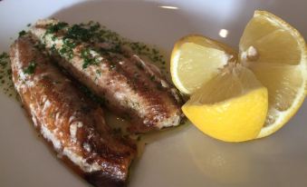 a white plate with two pieces of fish on it , accompanied by a slice of lemon at Ramsey House - Luxury Licensed B&B - Parking and Guest Lounge