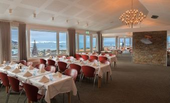 a dining room with tables and chairs set up for a formal event , featuring a view of the ocean at Hotel Arctic