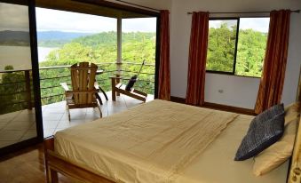 a bedroom with a large bed , chairs , and a table overlooking a beautiful view of the mountains at Drake Bay Getaway Resort