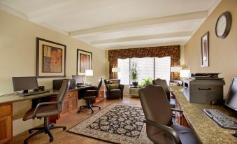 a well - furnished room with multiple desks , chairs , and a rug , all situated in front of large windows at Best Western Plus Madison-Huntsville Hotel