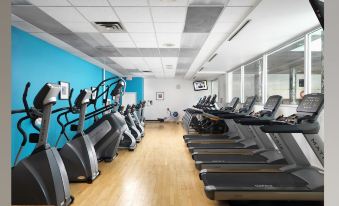 a gym with treadmills , stationary bikes , and other exercise equipment in a spacious room with blue walls at Regency Tirunelveli By GRT Hotels