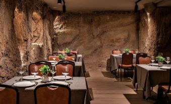 a restaurant with stone walls , wooden floors , and various dining tables set for guests to enjoy a meal at Hotel Gala