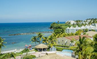 a tropical resort with white buildings , palm trees , and blue swimming pools , set against the backdrop of a clear blue sky at Aquarius Vacation Club at Dorado del Mar