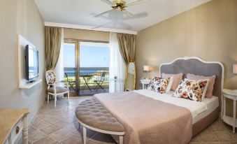 a luxurious bedroom with a large bed , two chairs , and a window overlooking the ocean at Hotel Carina