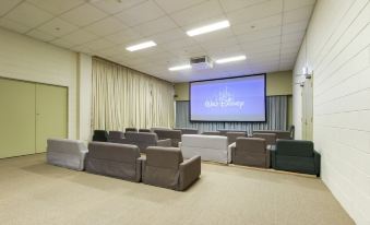 a large room with a projector screen and multiple couches , providing an intimate environment for relaxation and conversation at North Pier Hotel